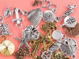 Closeup of gold and silver charms with anchors, starfish, leaves, and more.